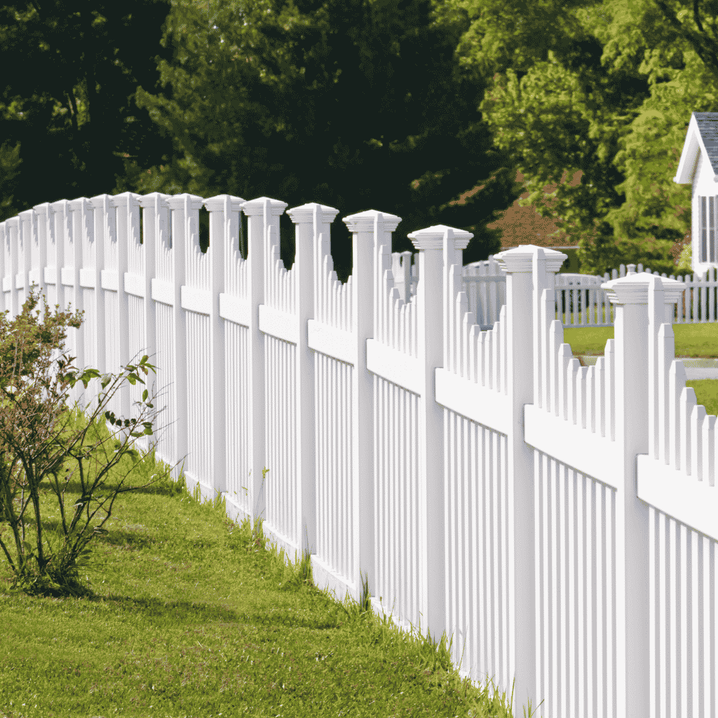 White pointed picket fence bordering a wooded front yard