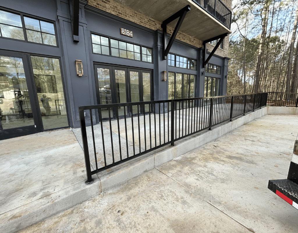 Black aluminum railing along a ramp at a modern commercial storefront