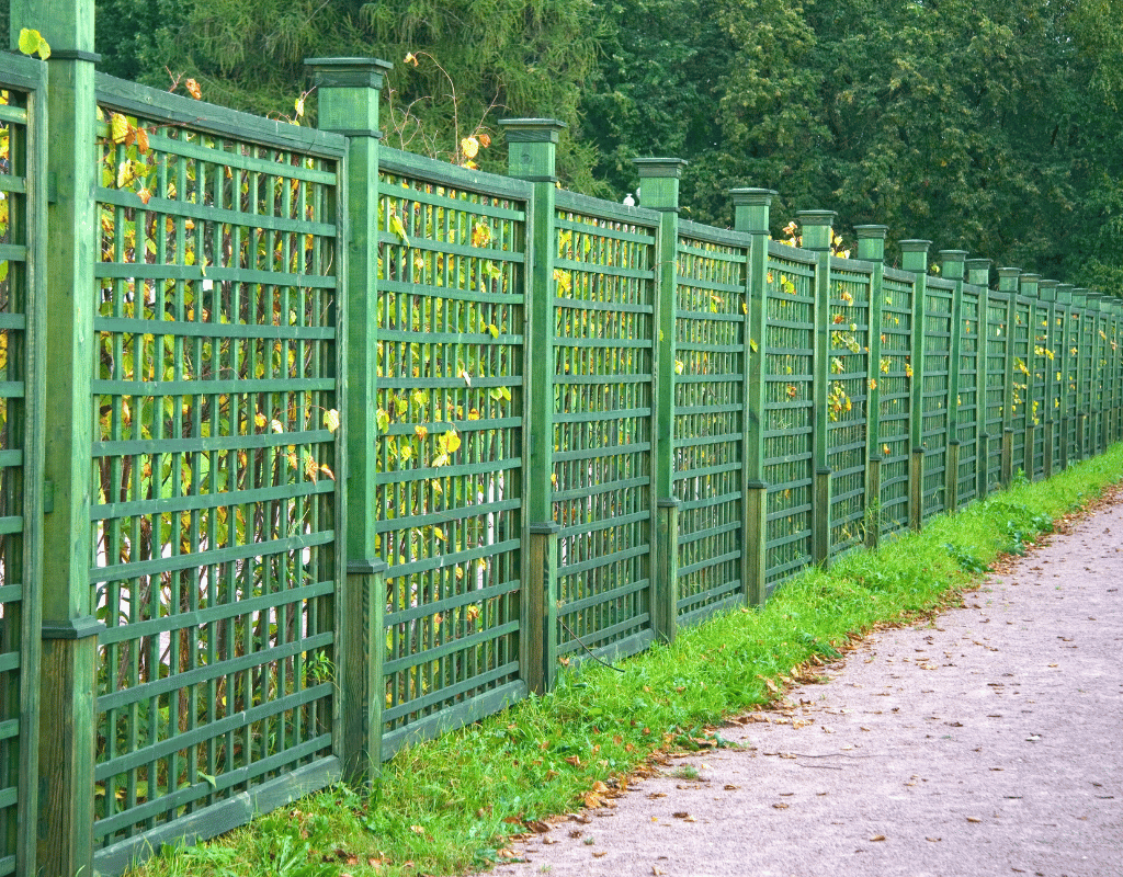 Green vinyl-coated chain link fence with lattice pattern along a paved walkway