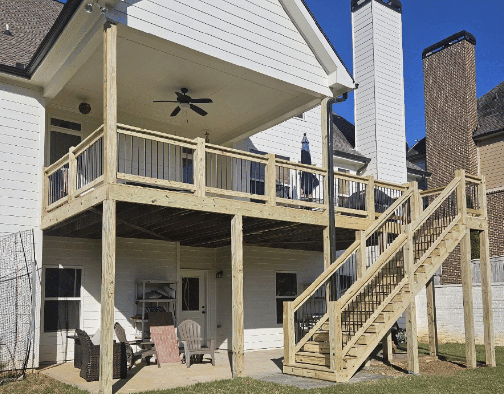 Two-story wood deck with railing and staircase attached to a home