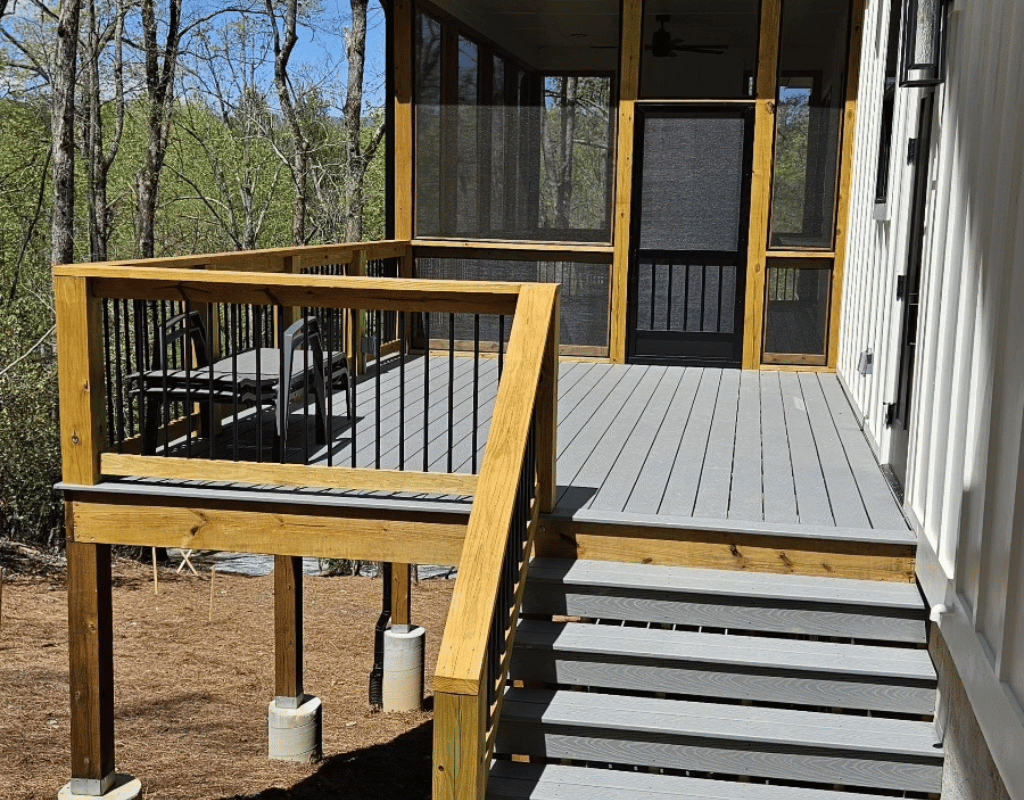 Wood deck leading to a screened porch in a wooded backyard
