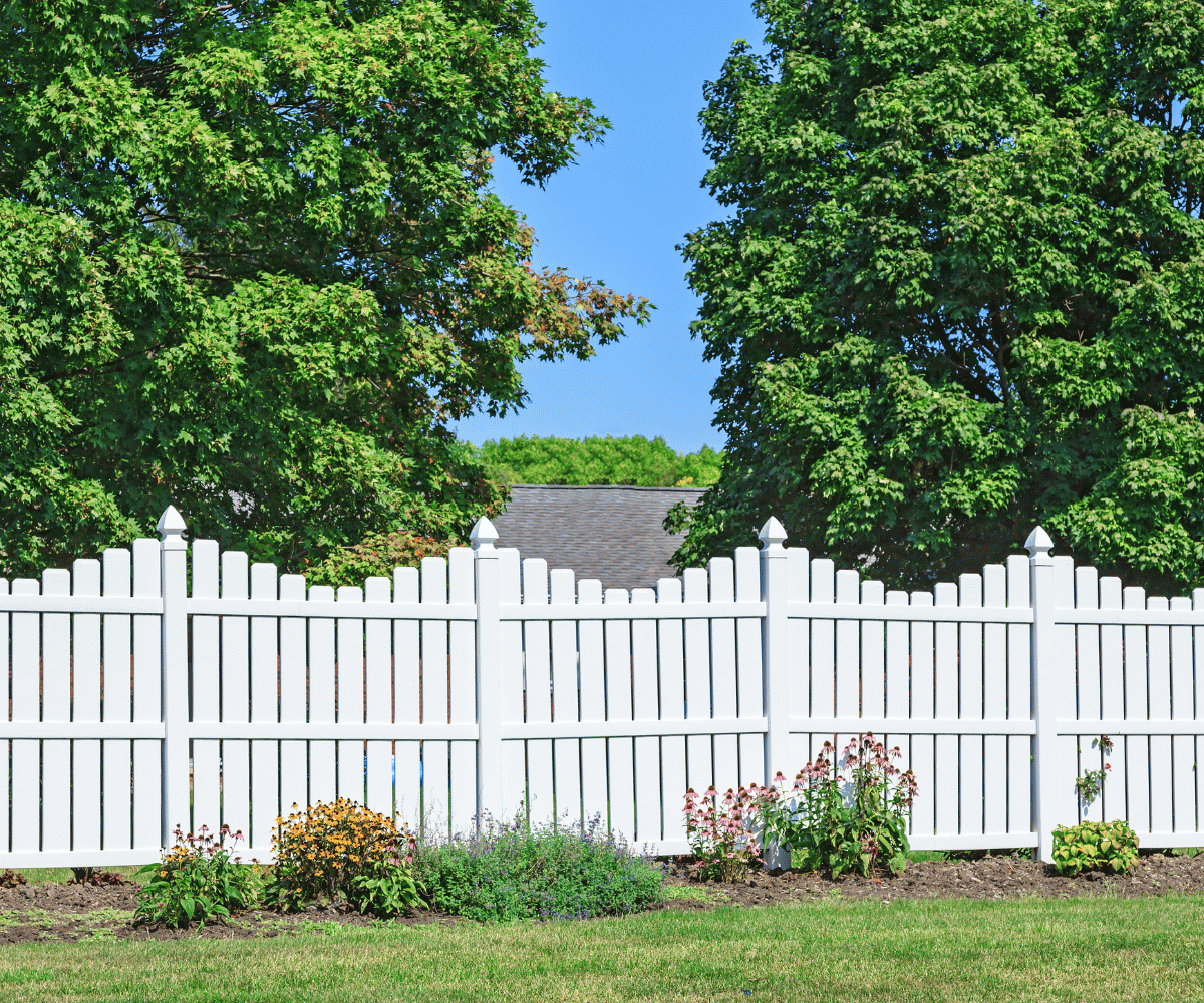 White picket fence bordering a flower garden in a residential front yard