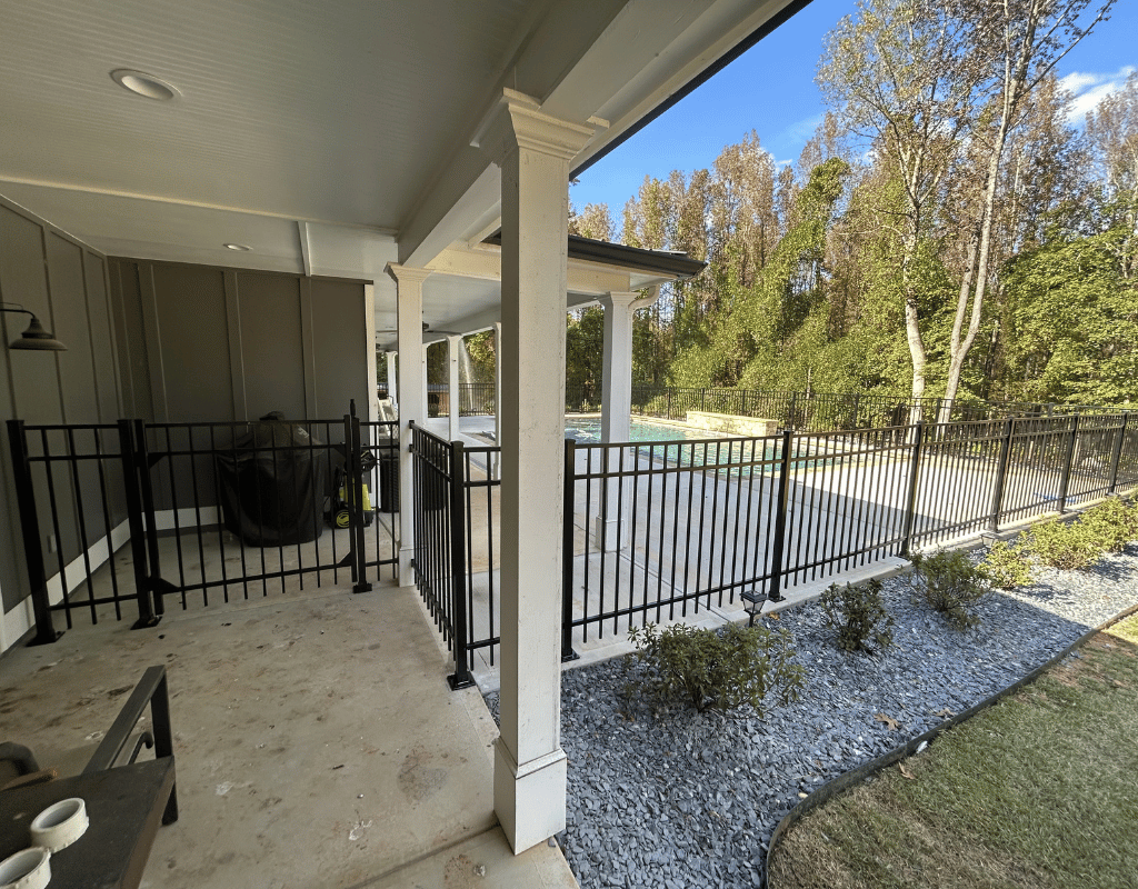 Black aluminum railing on a covered porch overlooking a backyard pool