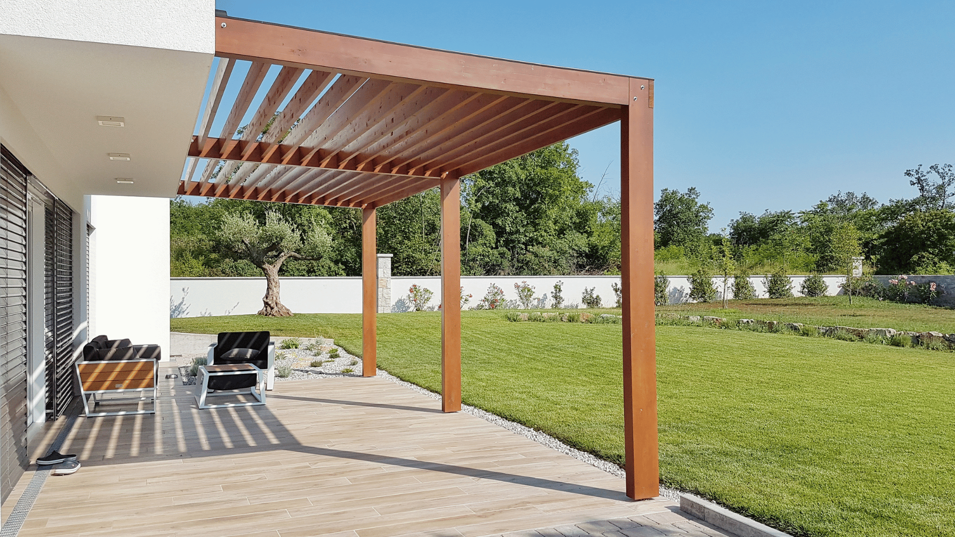 Modern wood slat pergola attached to a home patio overlooking a lawn