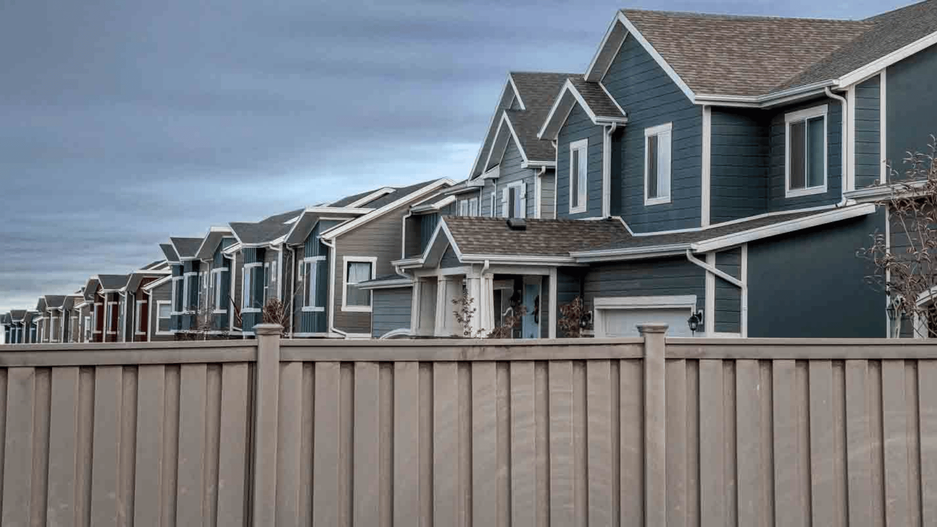 Tan composite fence installed in front of a row of townhomes