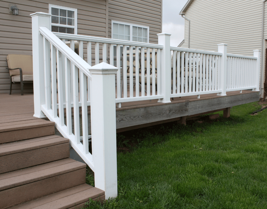 White vinyl railing along steps leading to a backyard deck