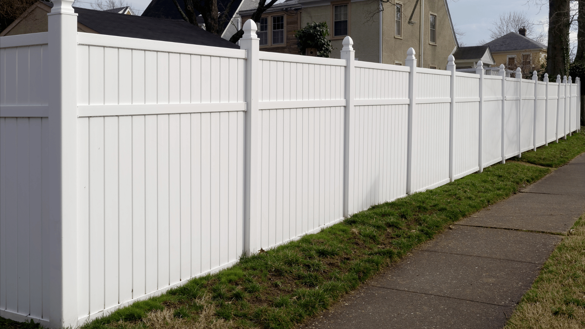 White vinyl privacy fence bordering a residential sidewalk
