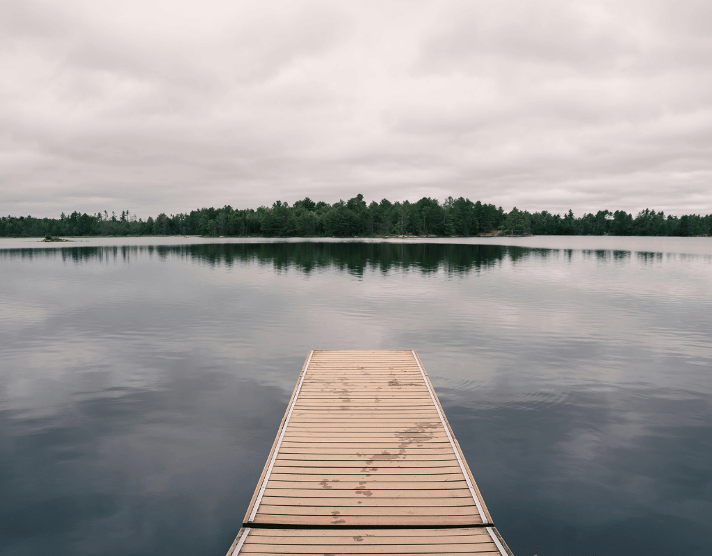 Wooden dock extending over a calm, tree-lined lake