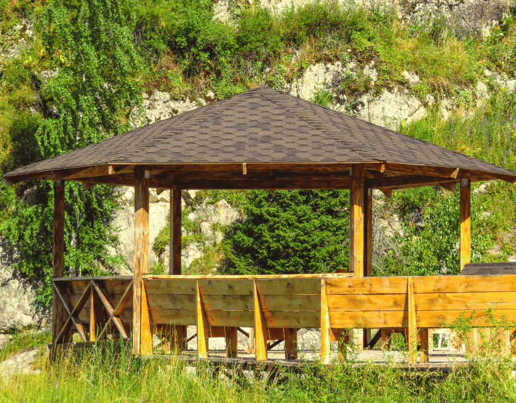 Wooden outdoor pavilion with shingled roof built into a rocky hillside