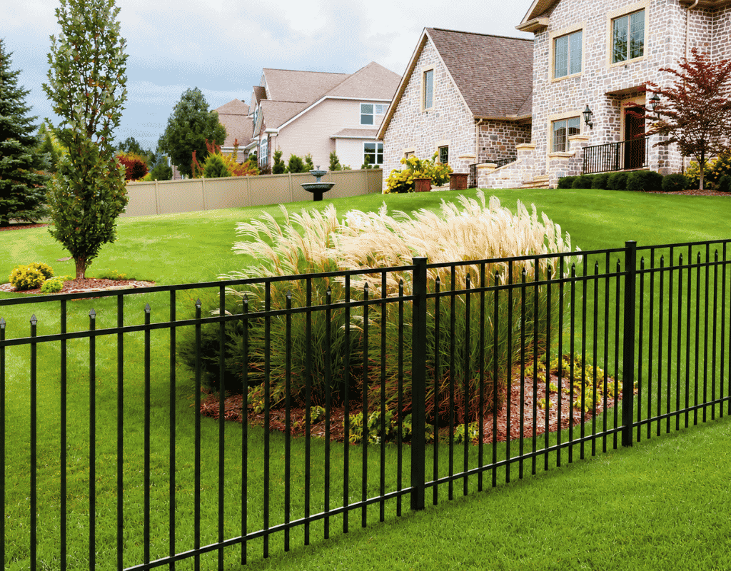 Black aluminum fence bordering a landscaped front yard with a stone home and fountain